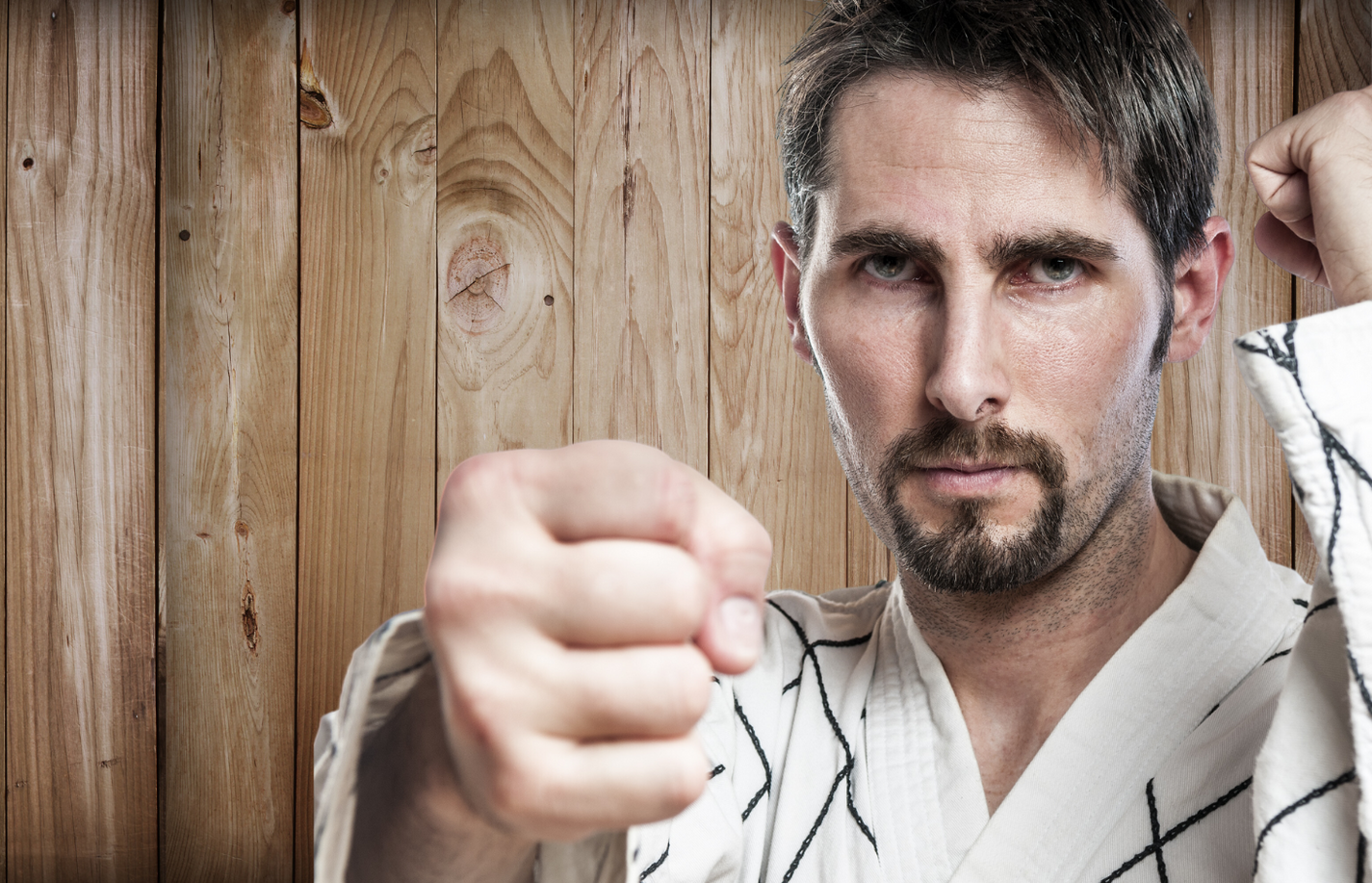 A man in a karate uniform is making a fist in the air.