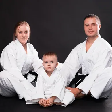 A man and a woman are sitting next to a child in karate uniforms