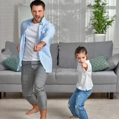A man and a little girl are dancing in a living room.