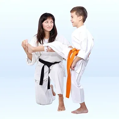 A woman is teaching a young boy how to do karate.