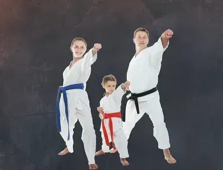 A family is practicing karate together in front of a blackboard.