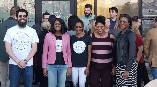 A group of people standing outside a building, several wearing branded shirts for 