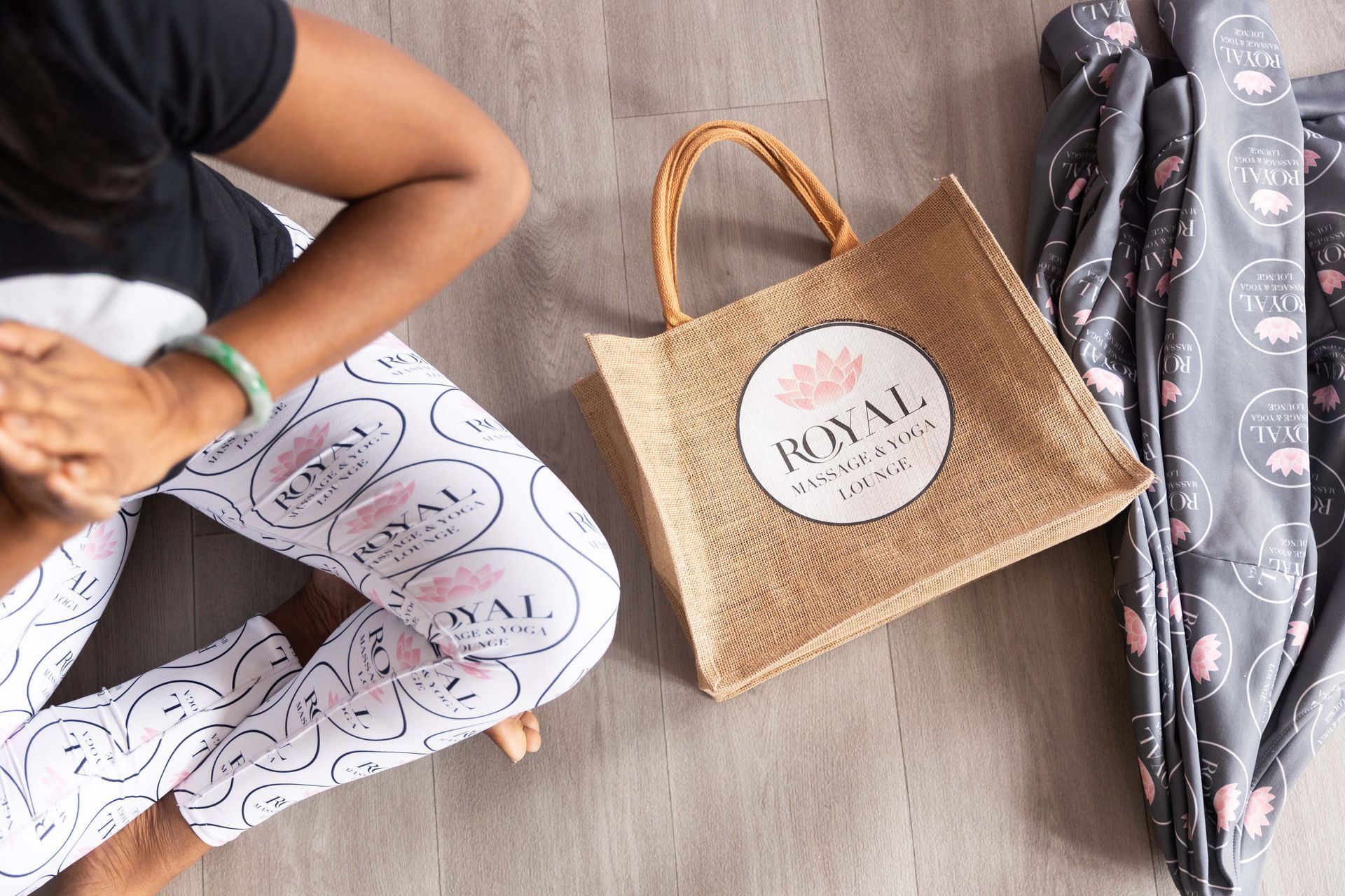 Person holding patterned gift bags beside a woven tote on a wooden floor.