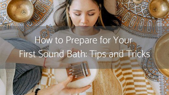 A person lies on a patterned blanket surrounded by singing bowls while someone plays a kalimba over them.