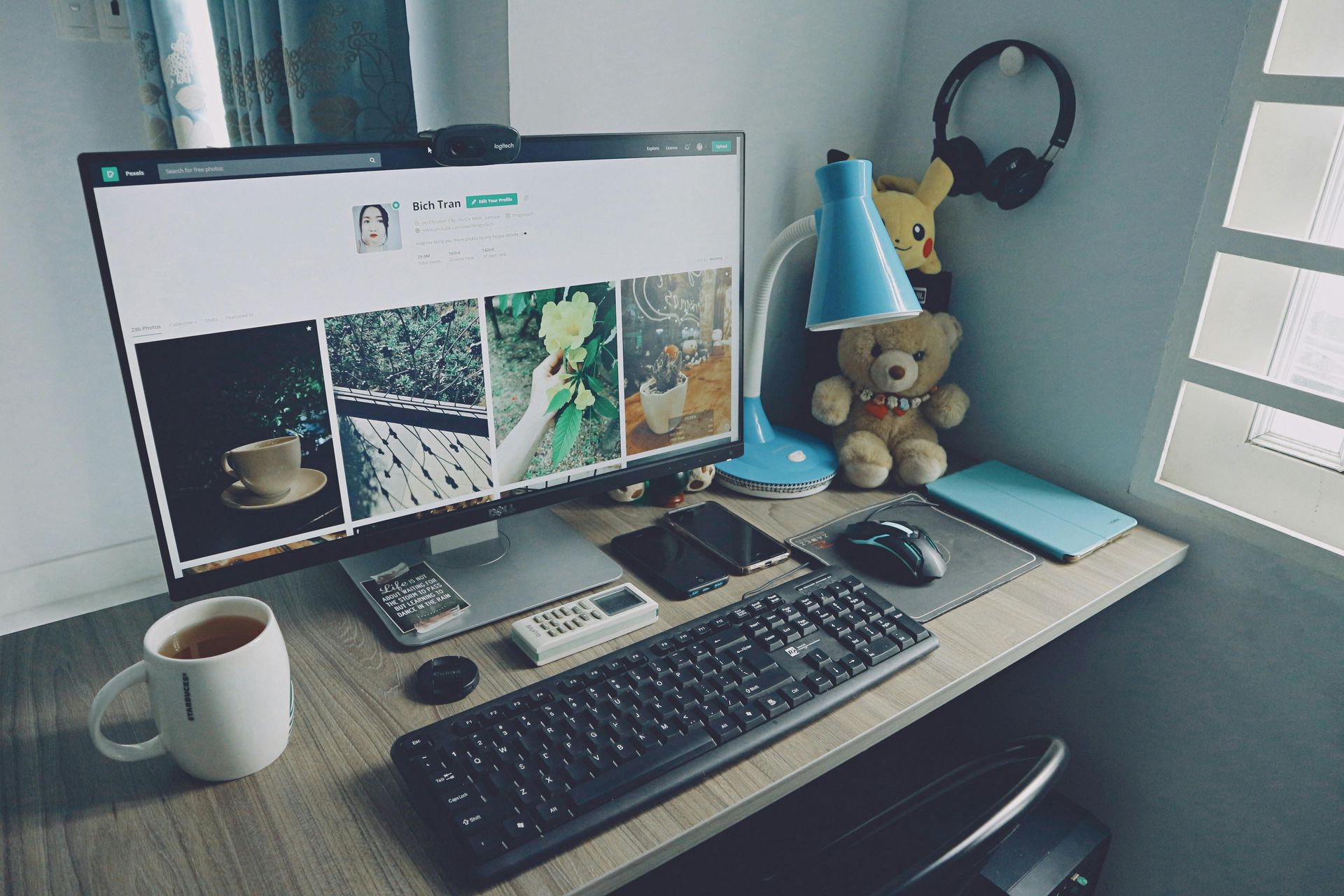 A computer is sitting on a desk next to a teddy bear.