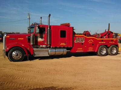 Red tow truck on dirt, labeled