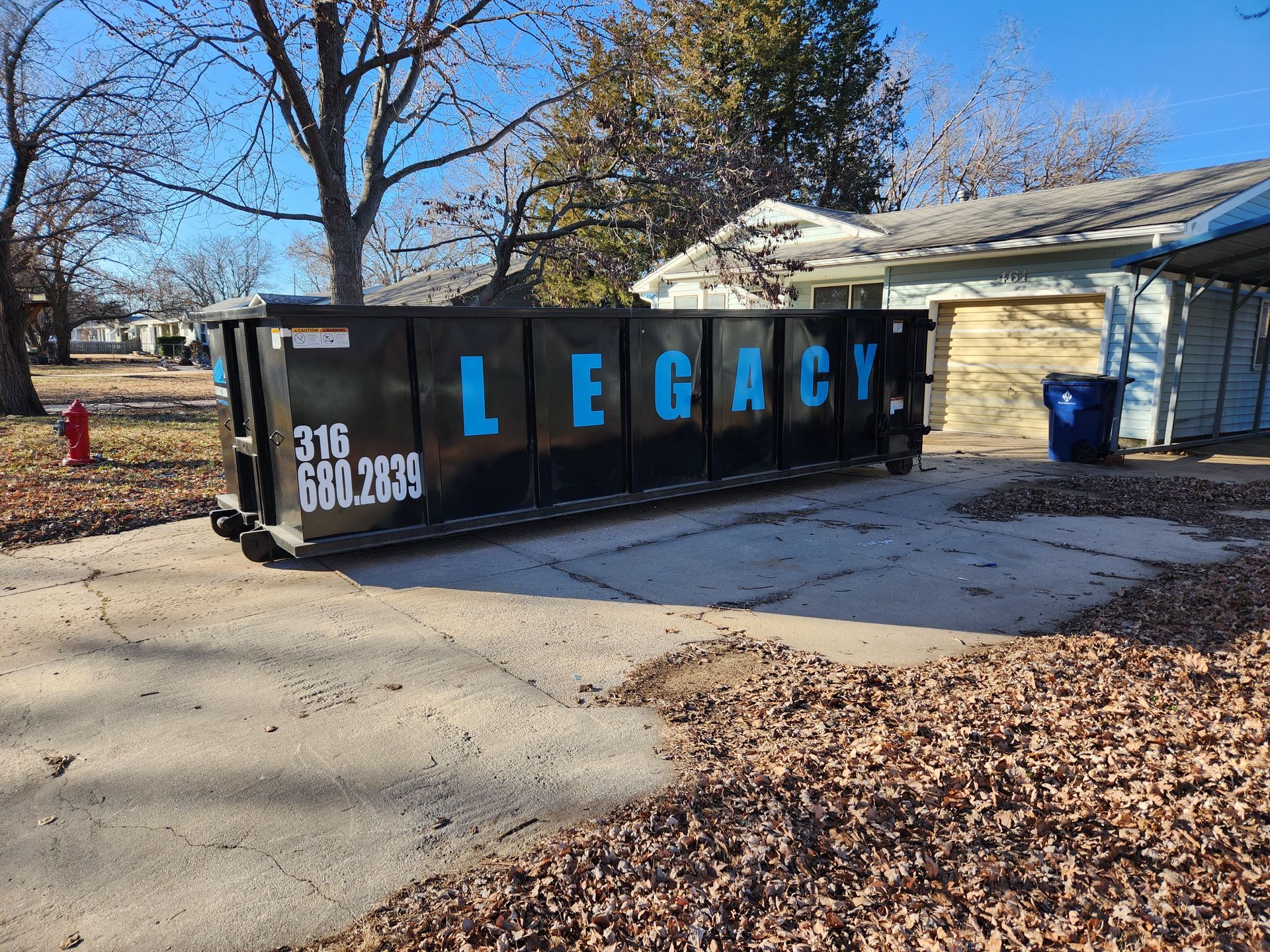 A large dumpster is parked in front of a house.