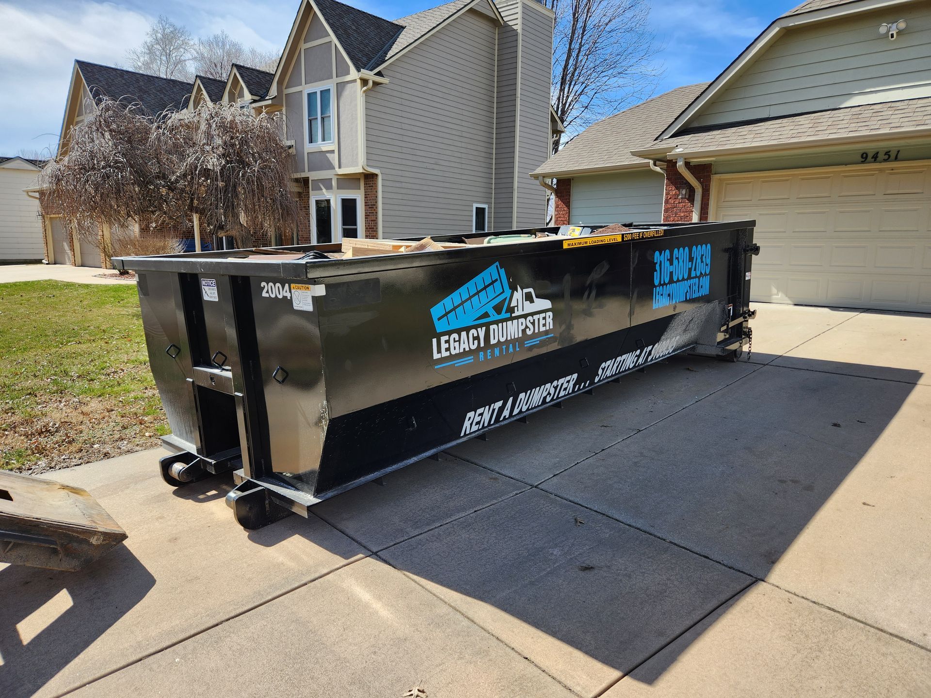 A dumpster is parked in front of a house.