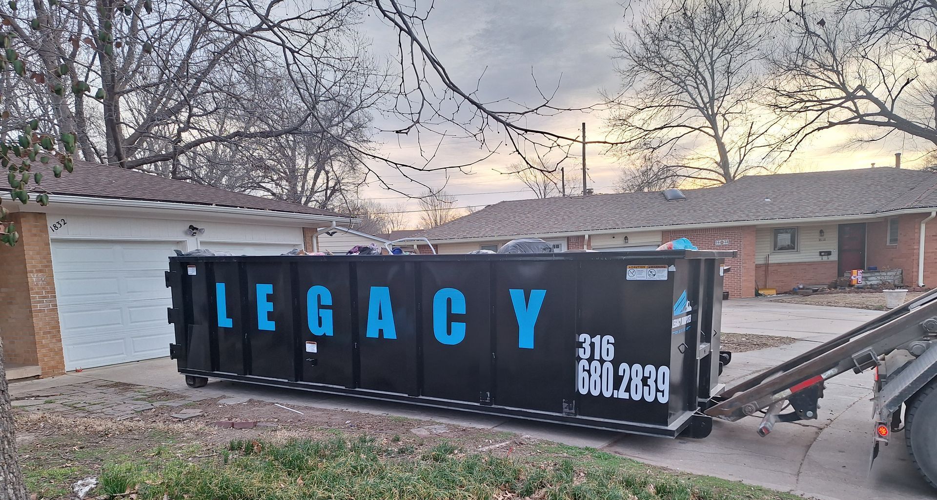 A dumpster is sitting in the driveway of a house.