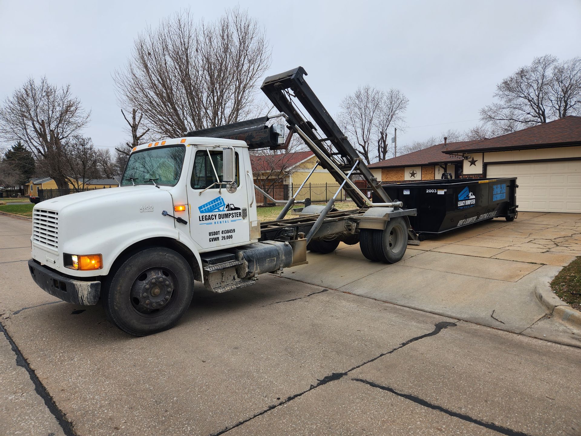A dump truck is dropping off a dumpster on a customers driveway in Wichita.