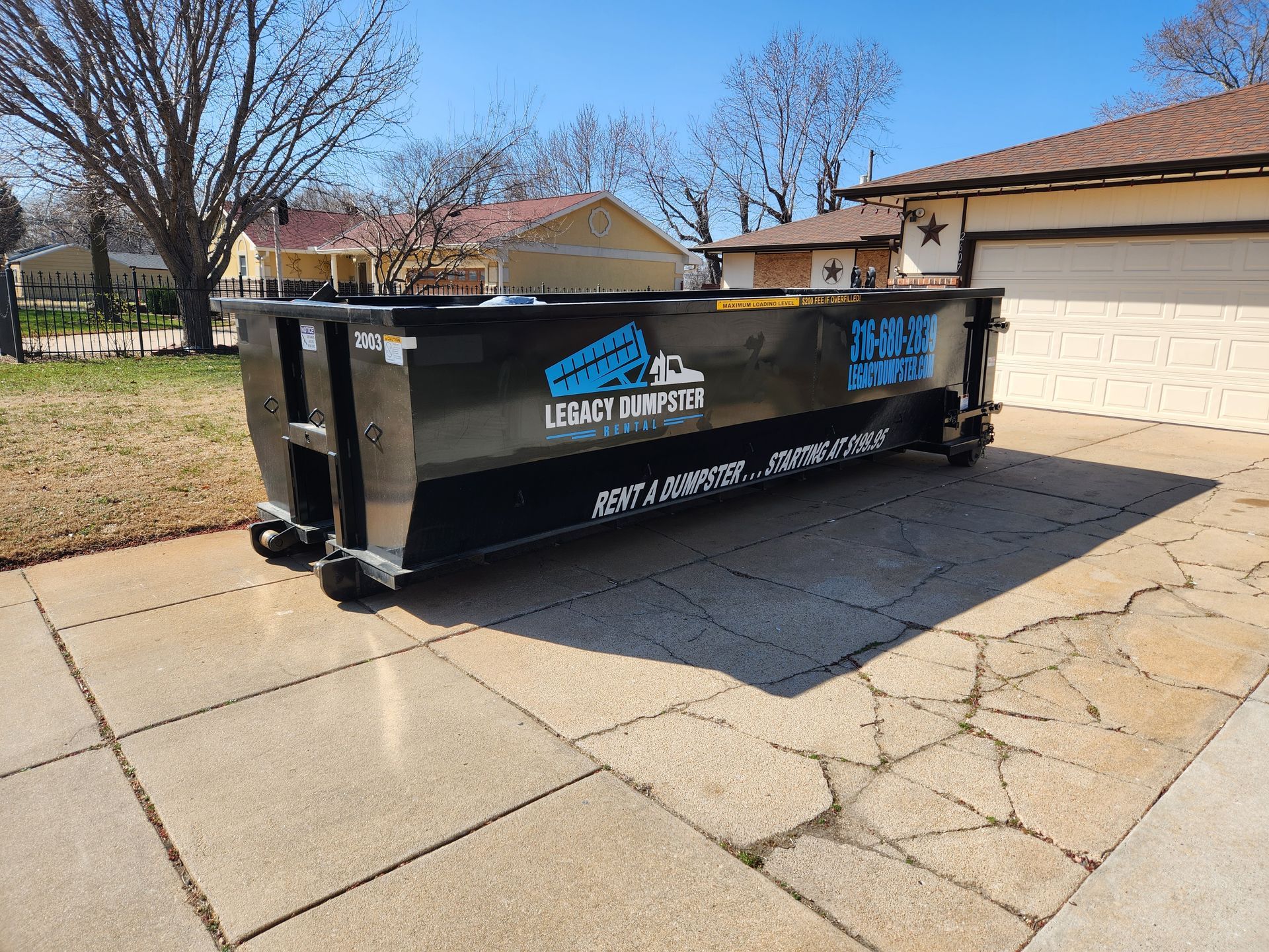 A 20 yard dumpster is parked in front of a house.