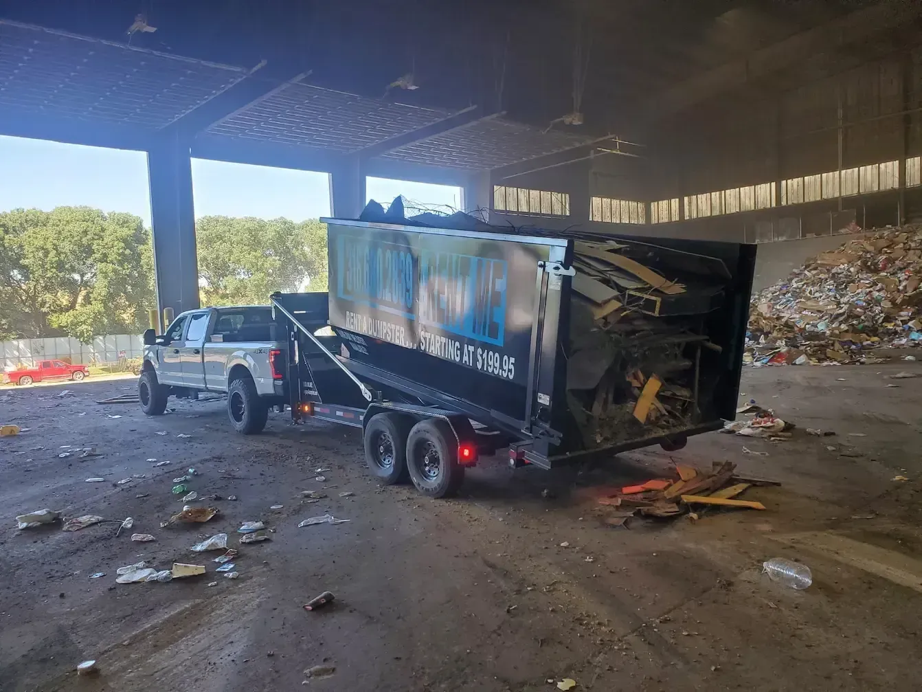 a dump truck is towing a dumpster in a field .