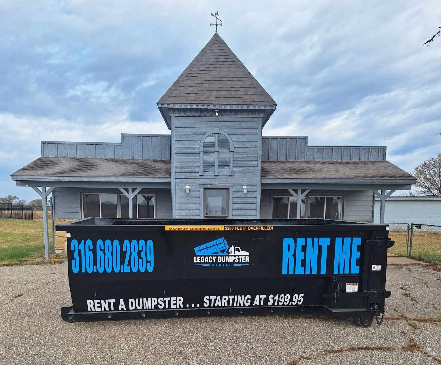 A dumpster that says rent me is in front of a building