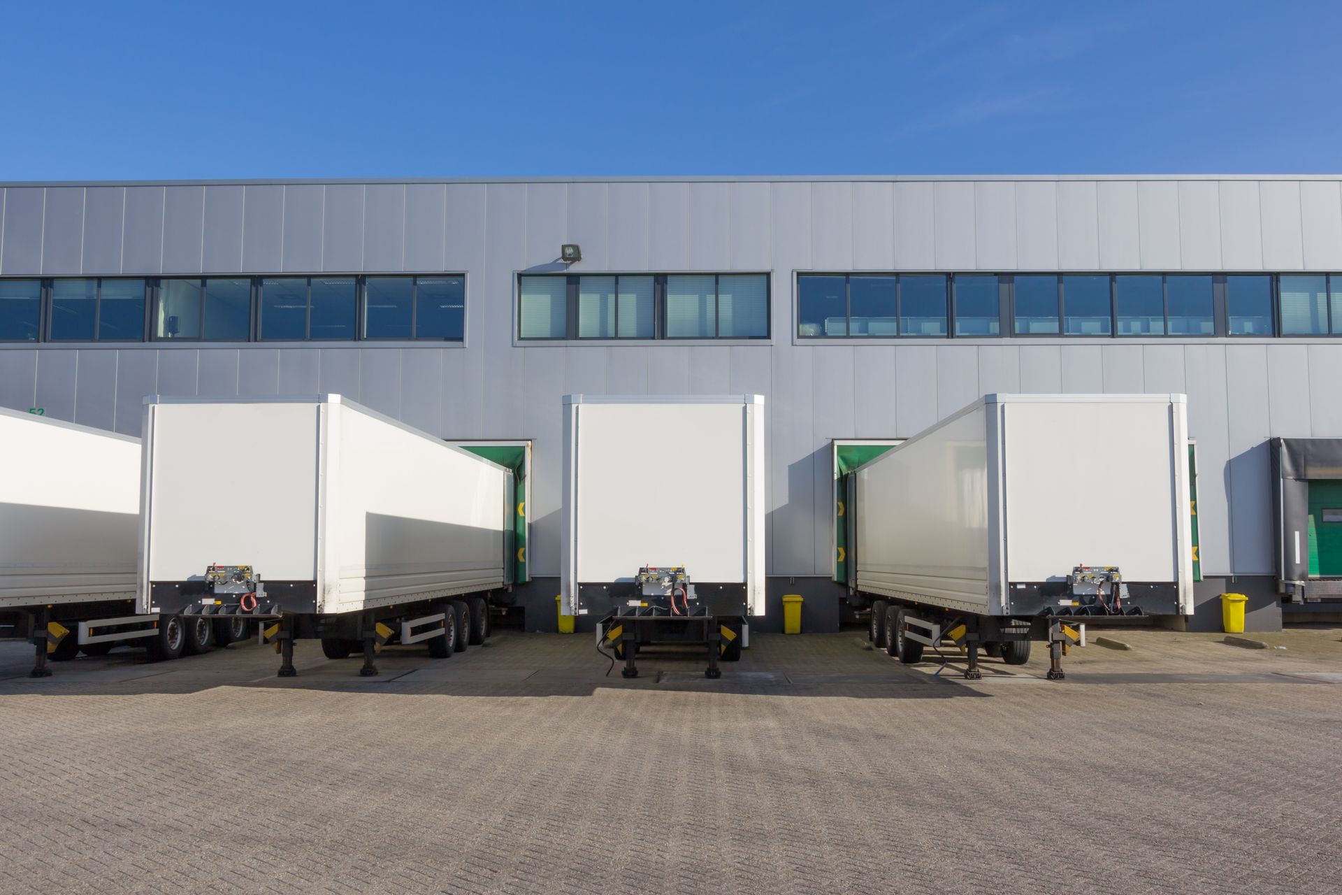 Open truck trailers at a loading dock. One contains boxes on a pallet.