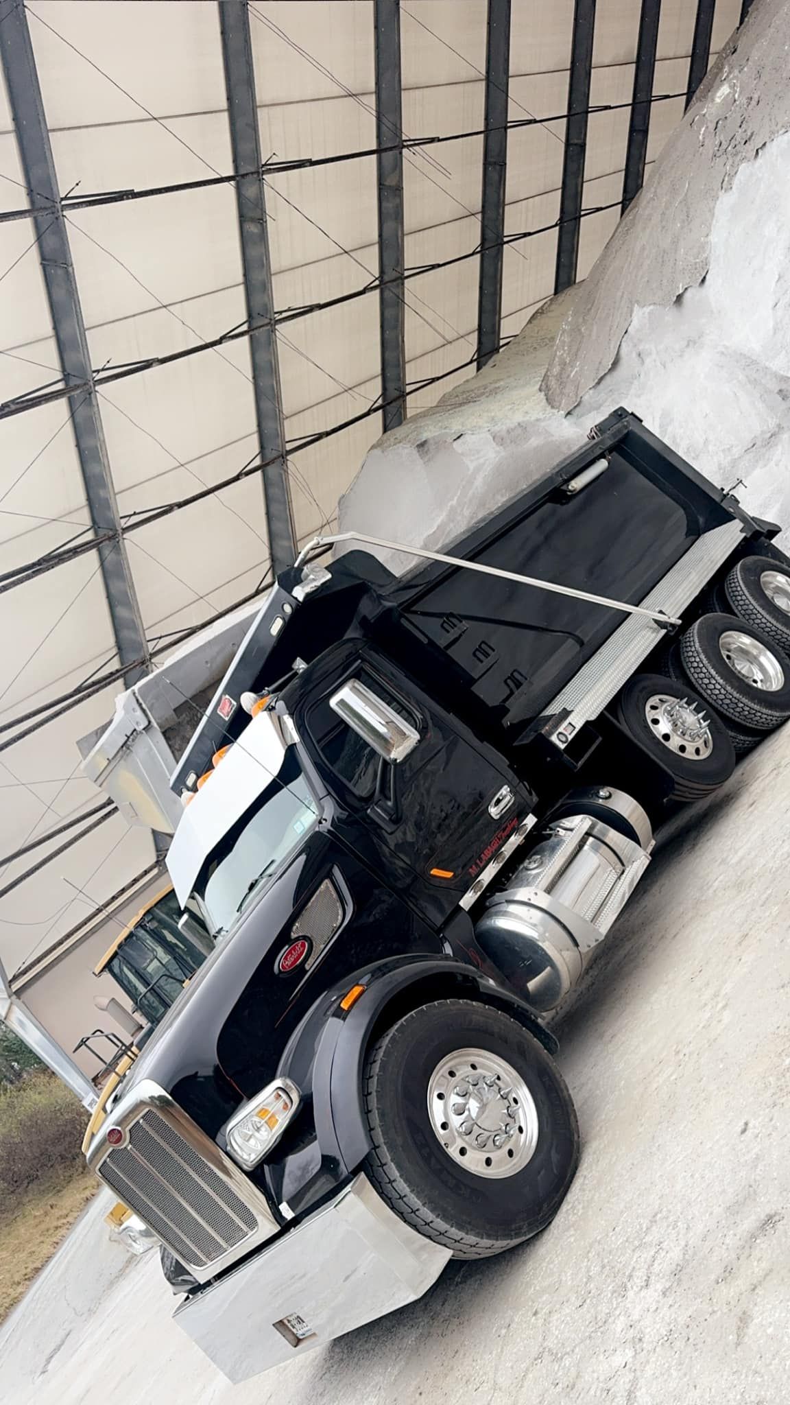 A dump truck is sitting on the side of the road next to a building.