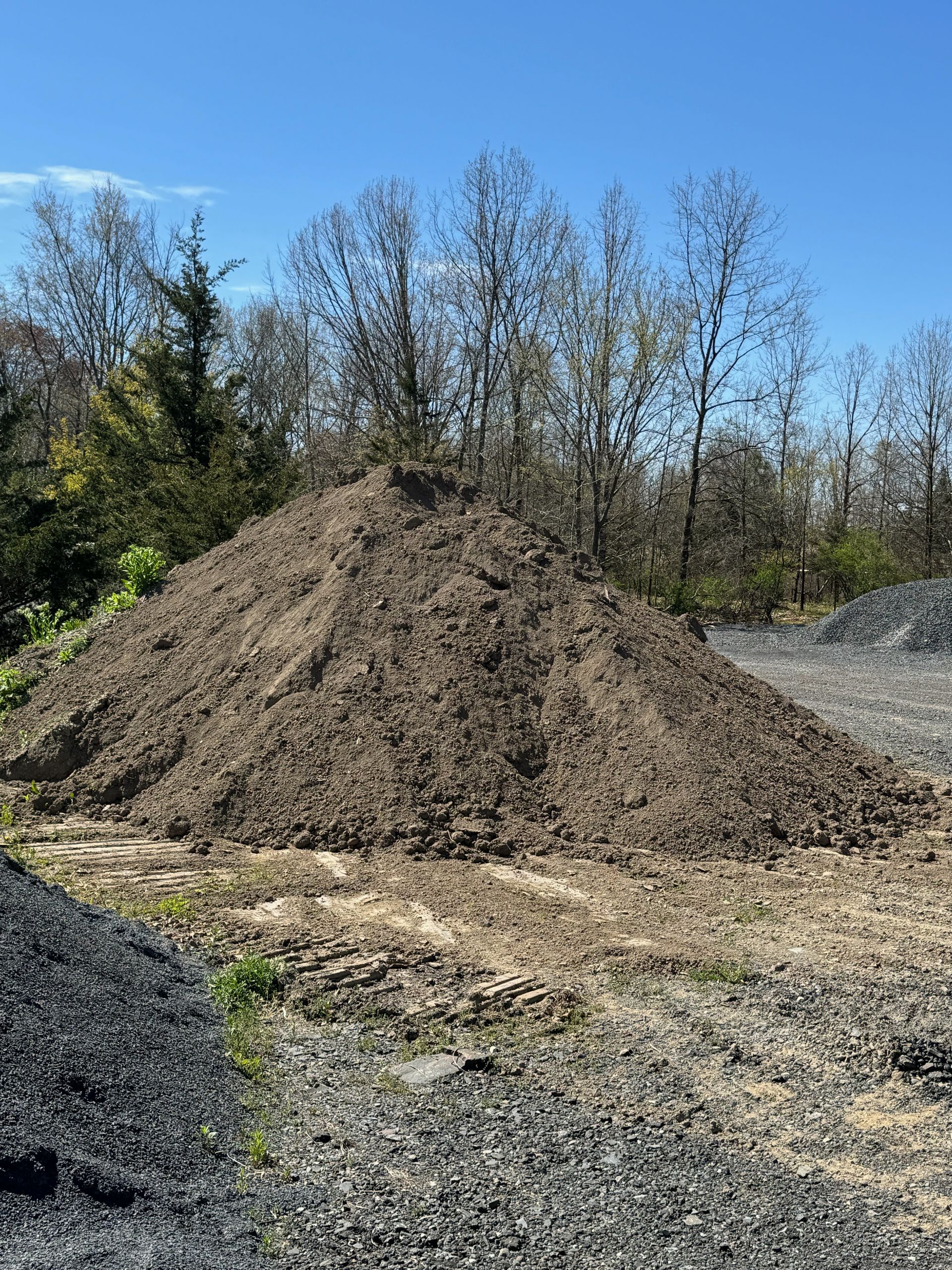 There is a large pile of dirt in the middle of a field.