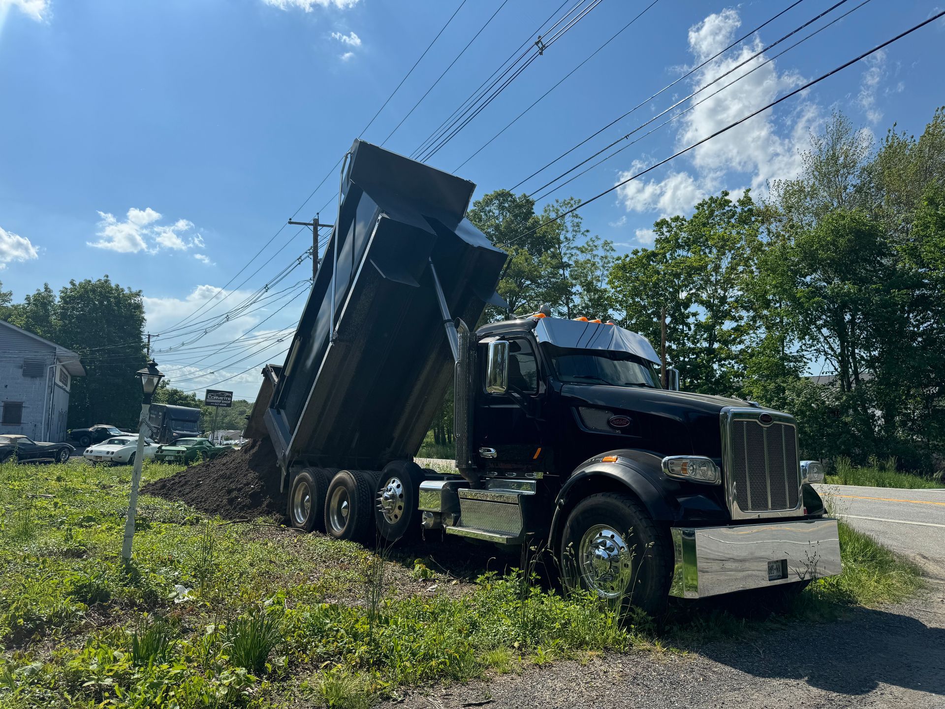 A black dump truck is parked in a grassy field.
