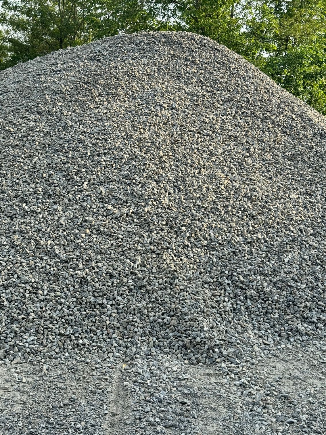 A large pile of gravel is sitting on top of a dirt hill.