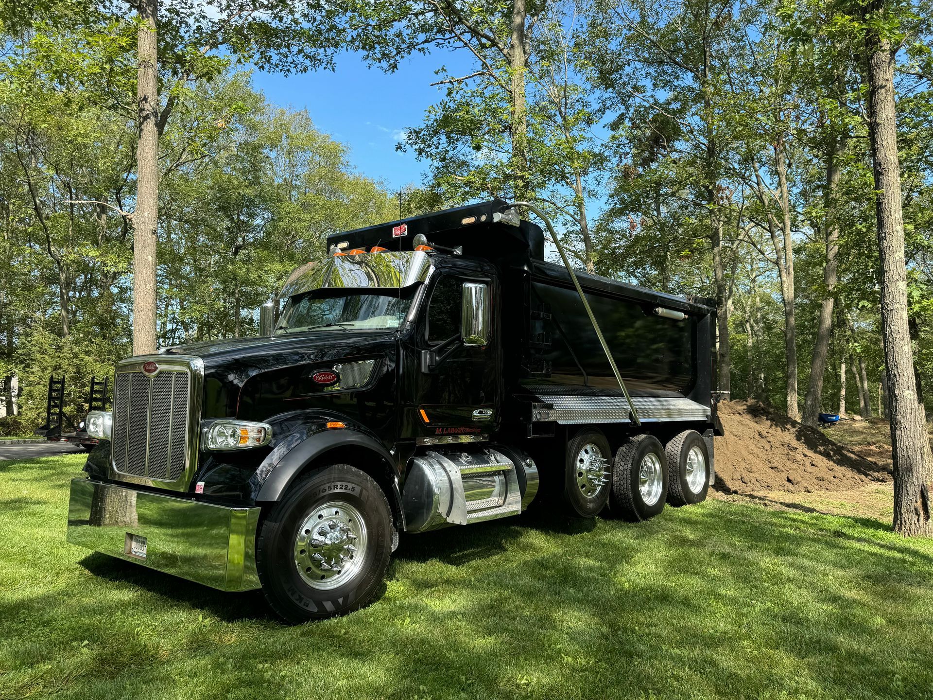 A black dump truck is parked in a grassy field.