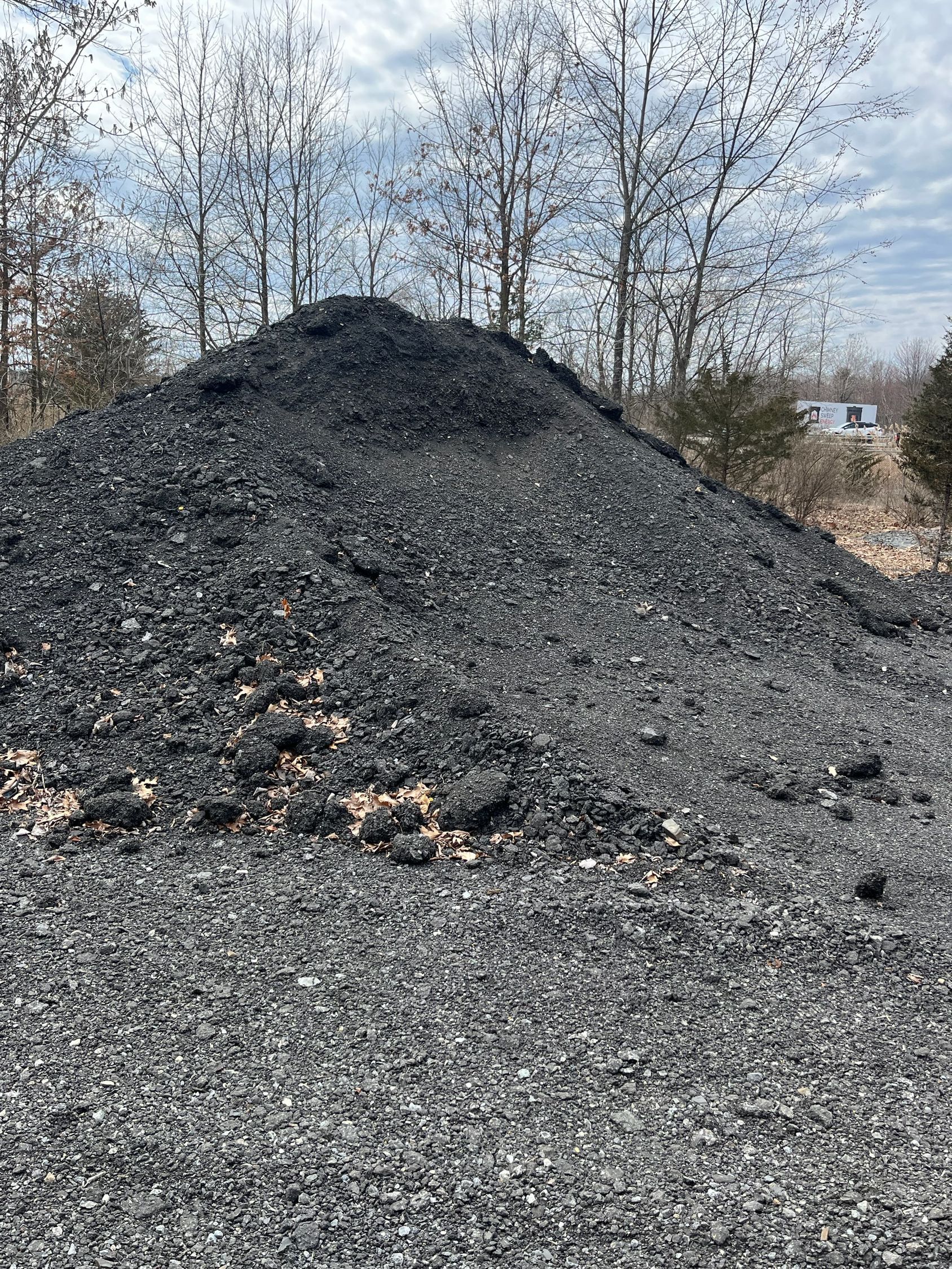 A large pile of coal is sitting on top of a dirt field.