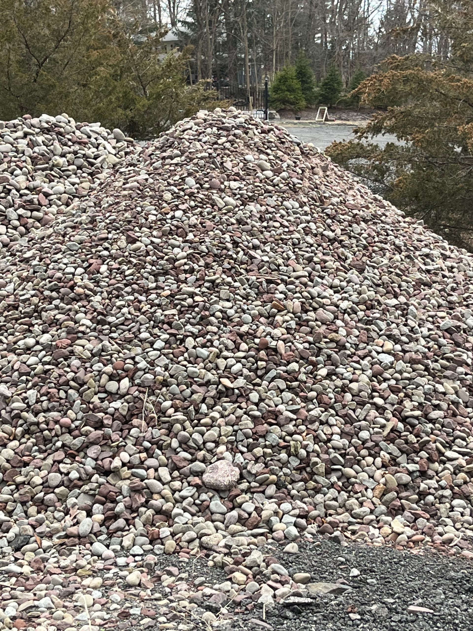 A large pile of gravel is sitting on the side of a road.