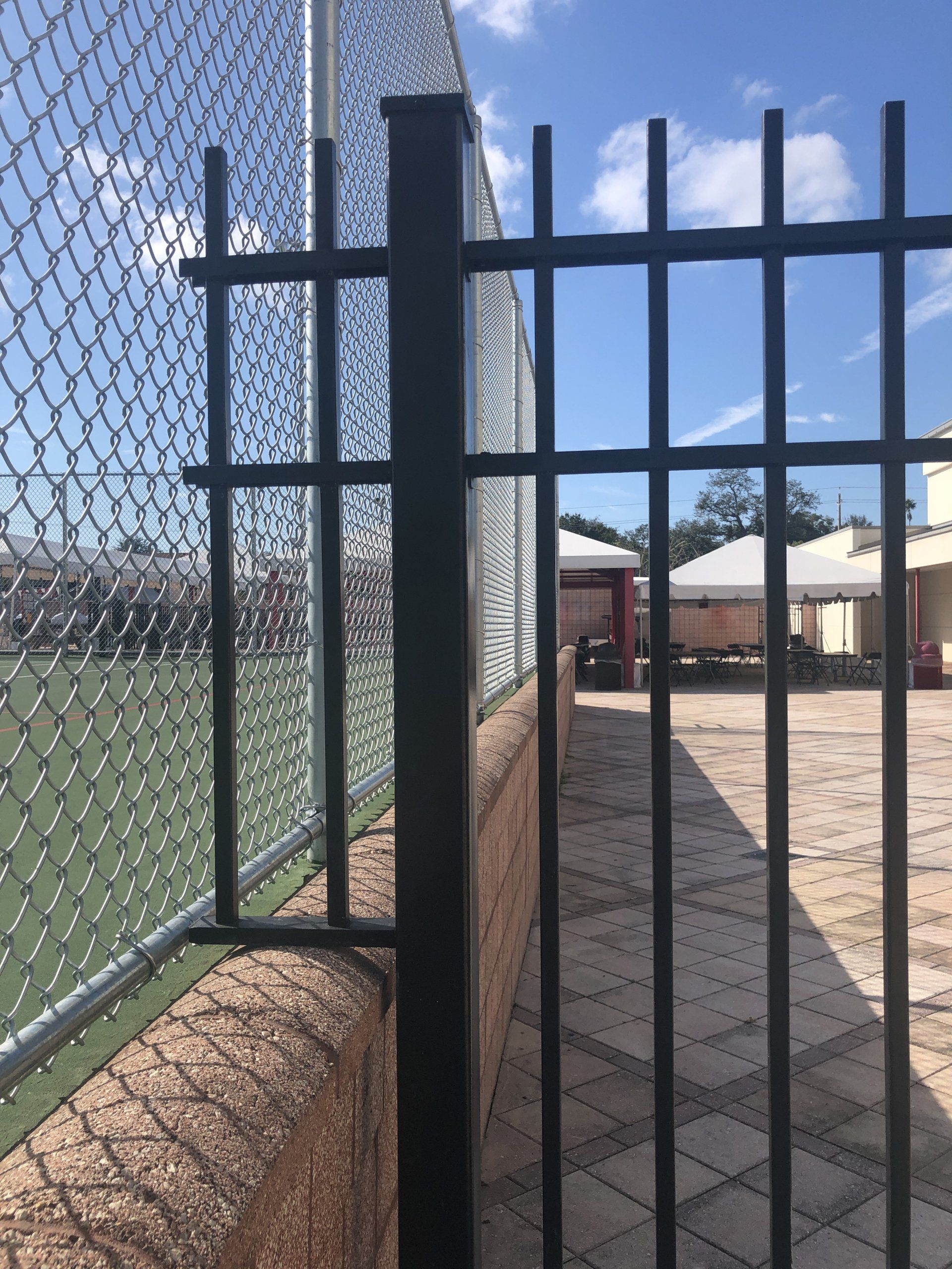 Custom-designed black steel fence seamlessly fitted around a secure wall