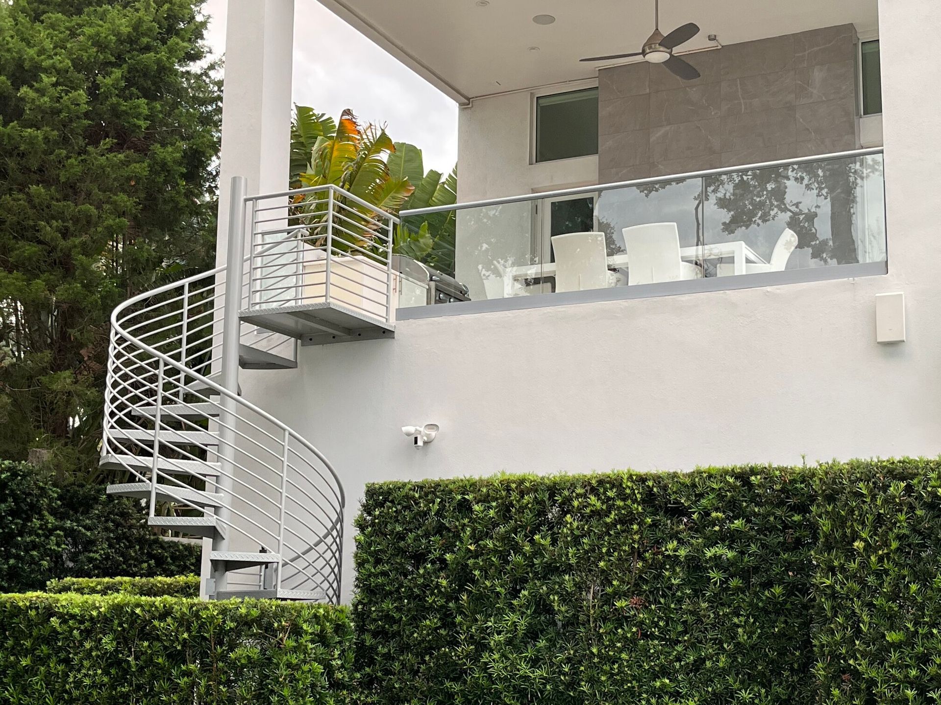 luxury home with spiral stairs leading to outdoor kitchen and dining area on deck