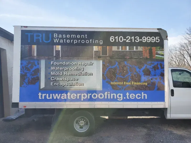 A white work truck parked outdoors displaying branding for 