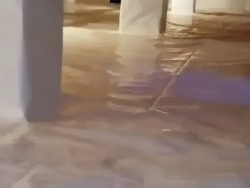 A flooded indoor space with water covering the floor and reflecting light, seen from a low perspective.
