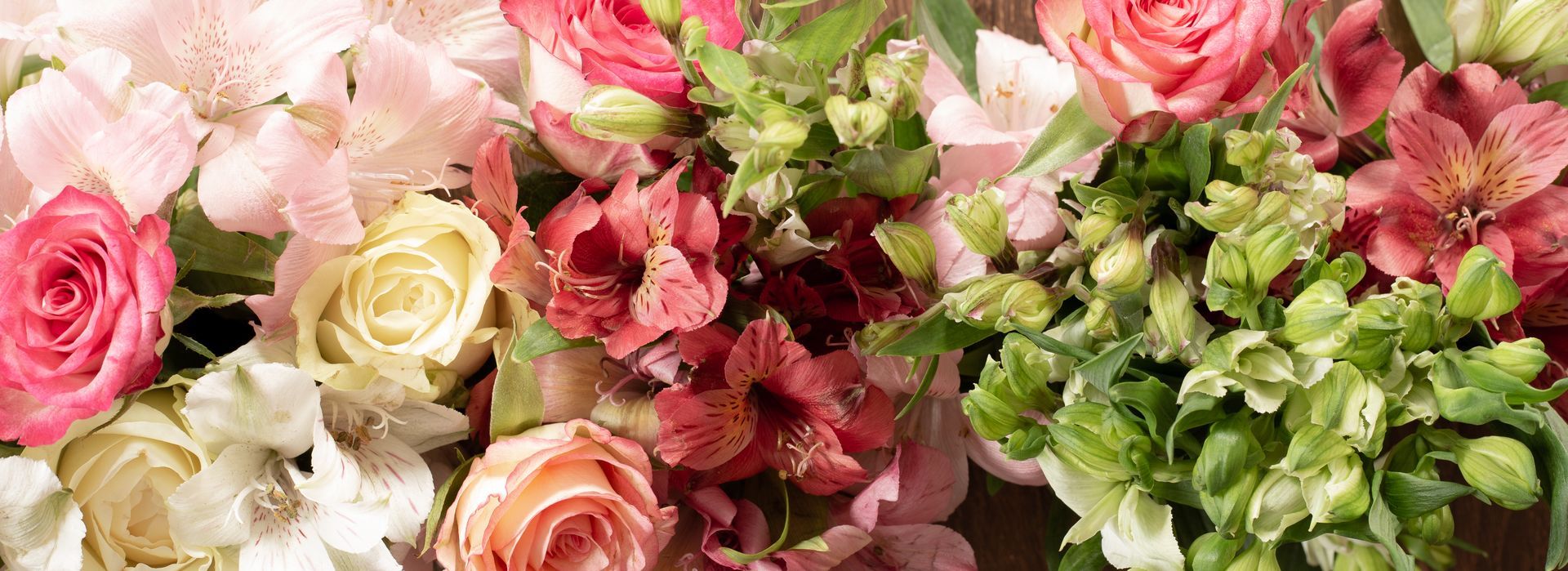 Assorted pink, cream, and green roses arranged in a floral bouquet