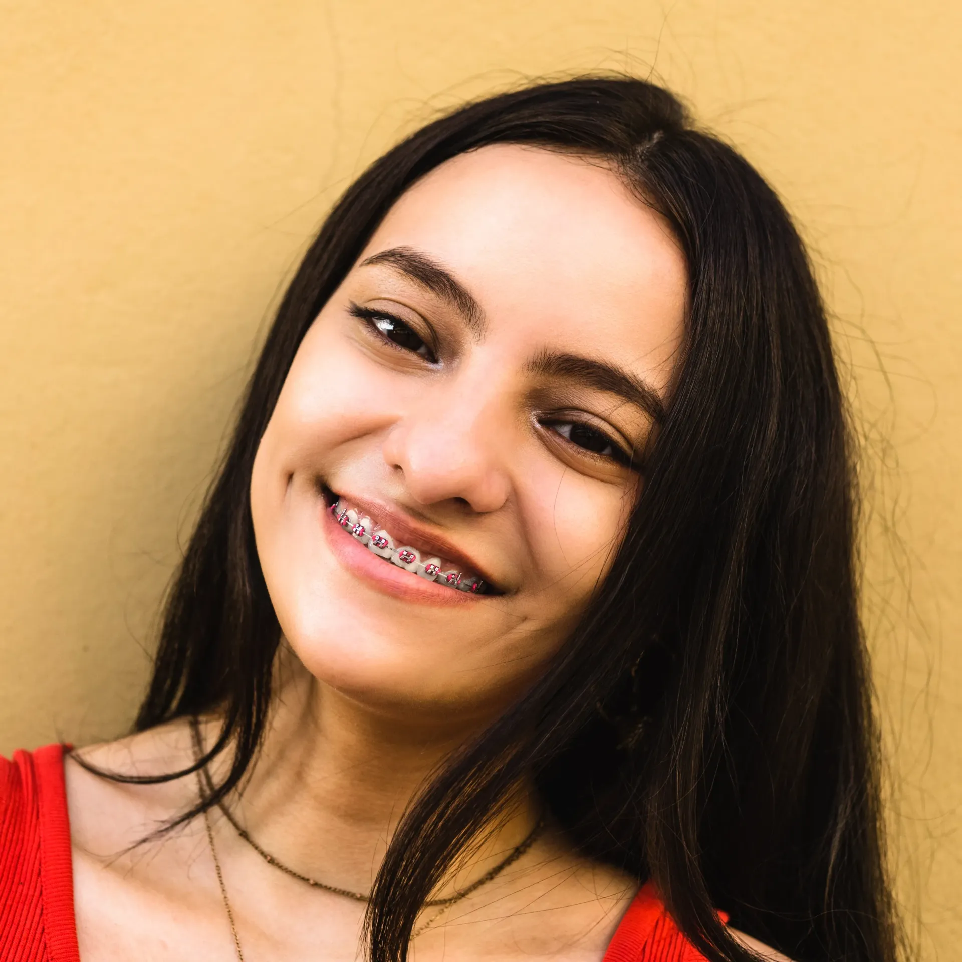 A woman with braces on her teeth is smiling for the camera.