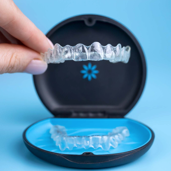 hand holding invisalign aligner in front of invisalign aligner case