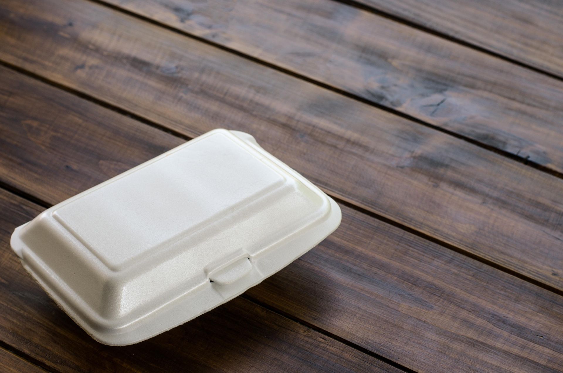 White takeout container on a wooden table.