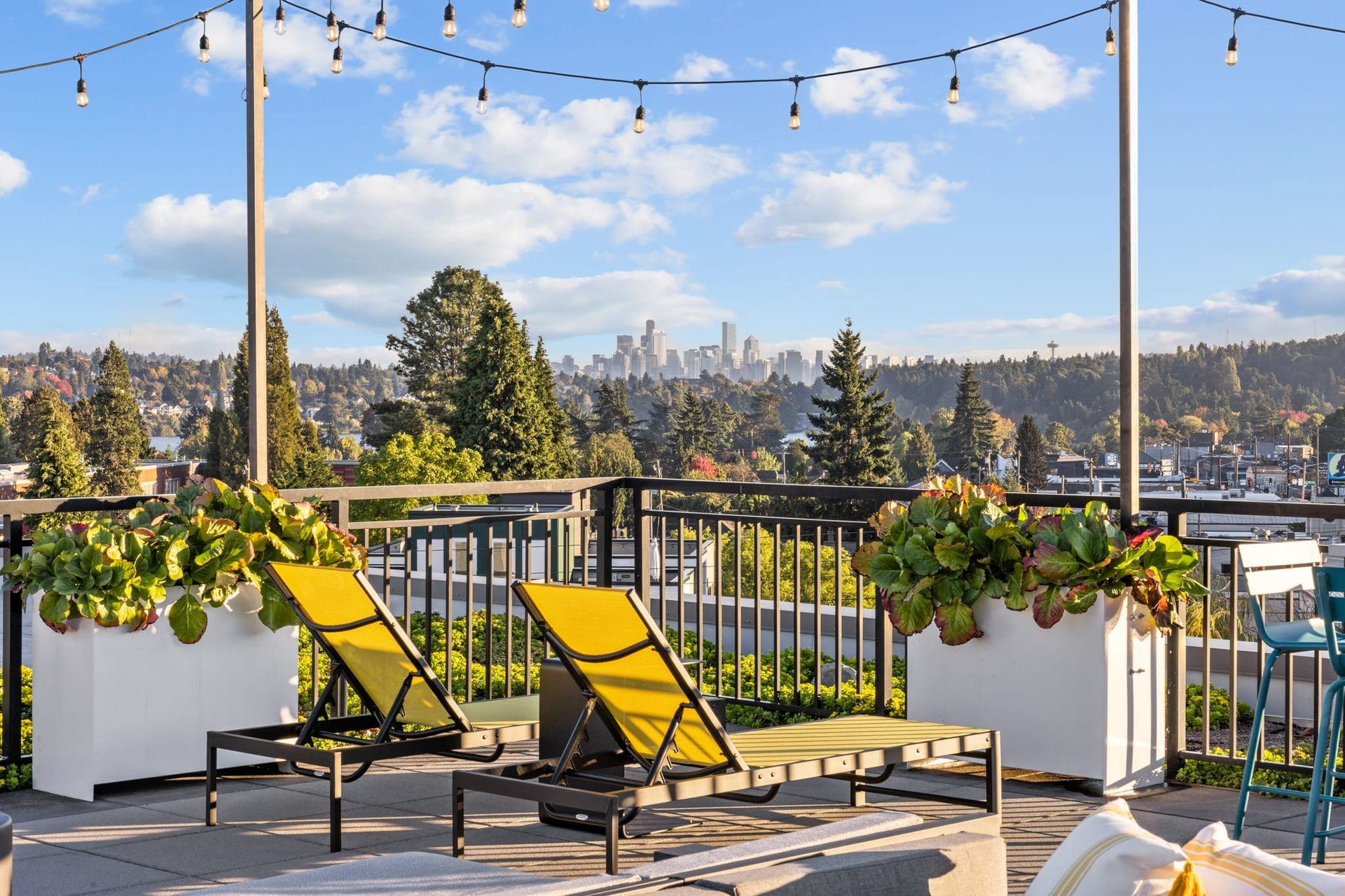 There are two yellow lounge chairs on the balcony with a view of the city.