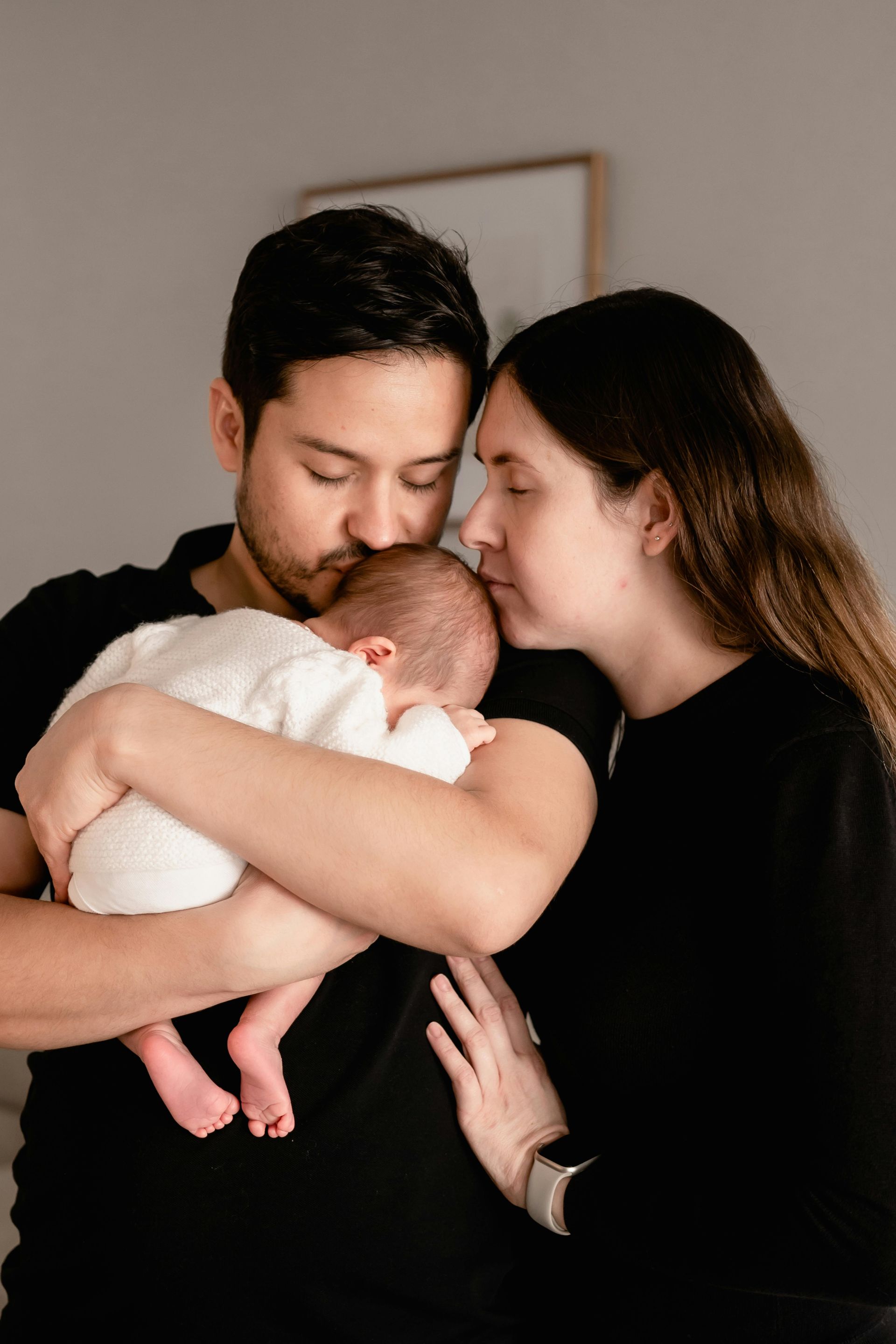 Overwhelmed parents holding their baby during postpartum, showing the emot