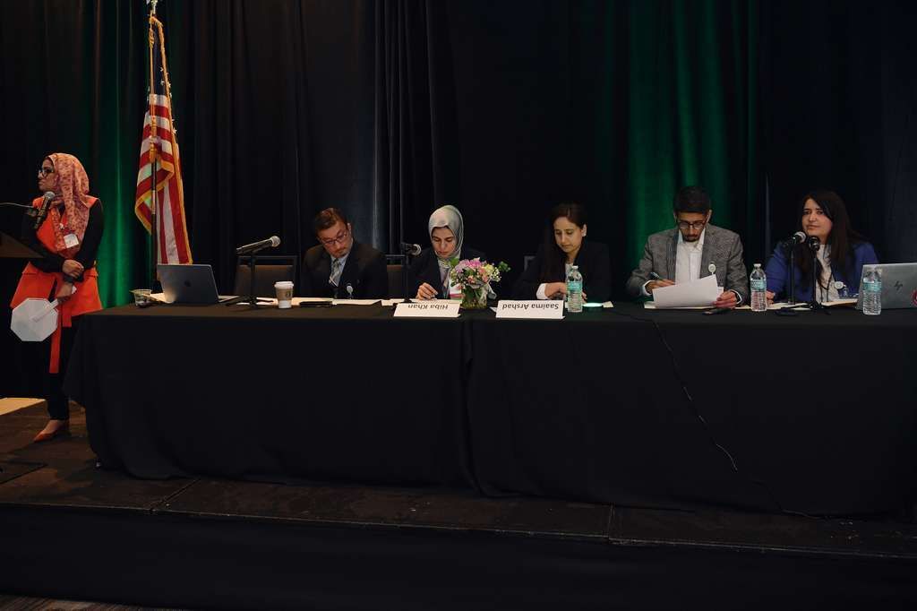 A person speaking at a podium in front of a circular banner featuring the flags of Ohio and Pakistan with the APPNA-NEO logo.