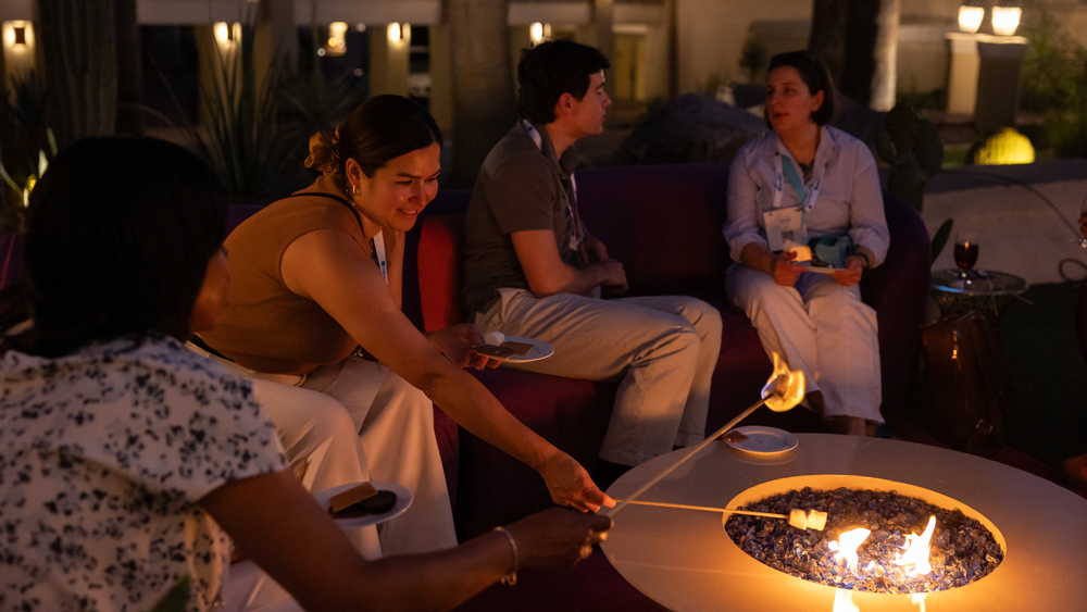 Friends chatting by a fire pit on a warmly lit patio at night
