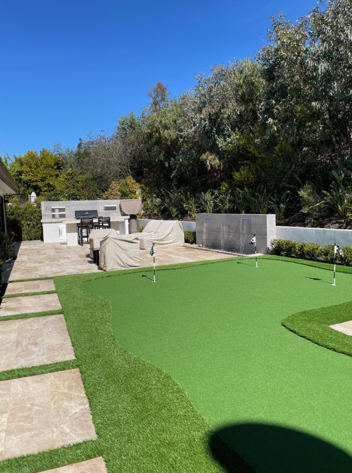 There is a putting green in the backyard of a house.