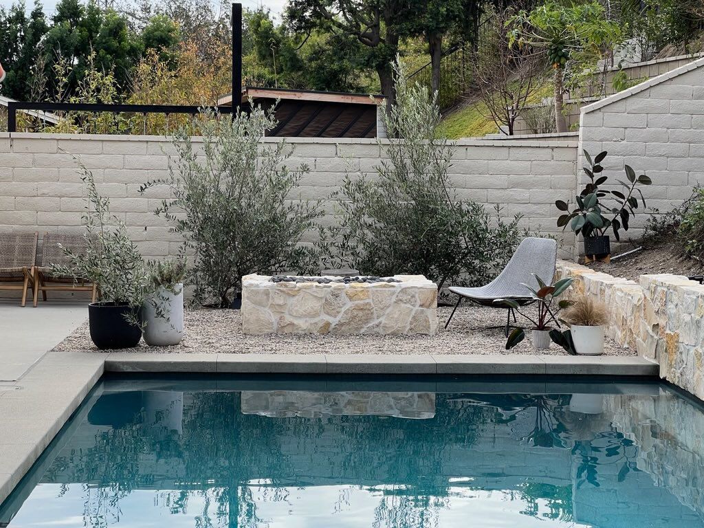 A large swimming pool with a fire pit in the backyard.