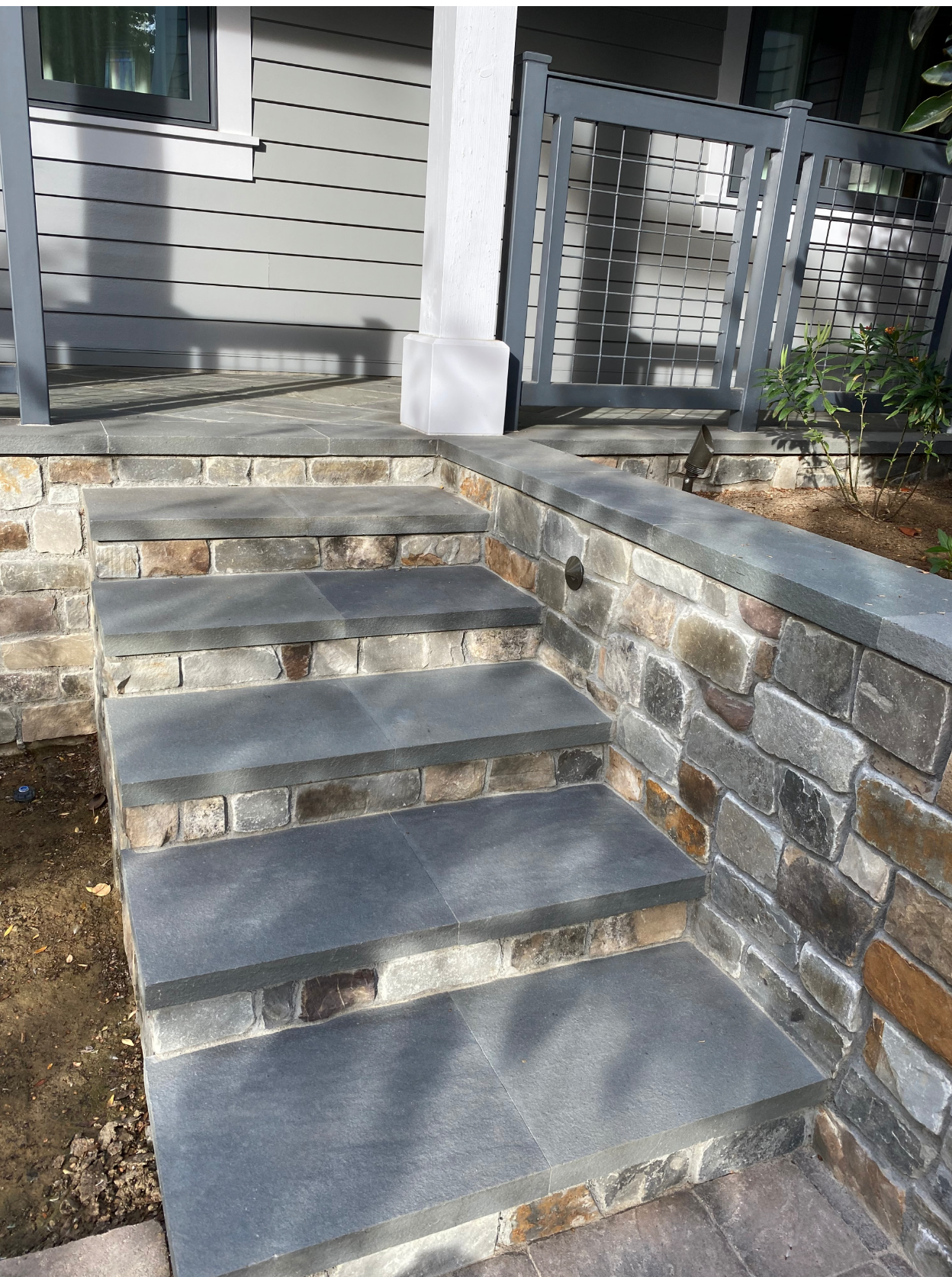 A set of stairs leading up to a stone wall in front of a house.