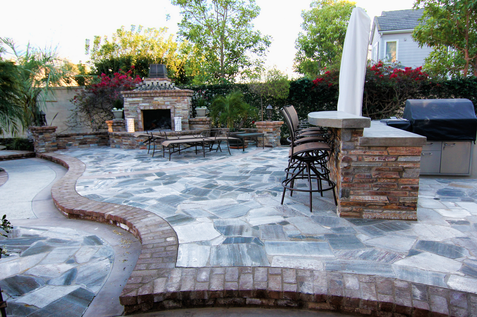 A patio with a fireplace , table , chairs and umbrella.
