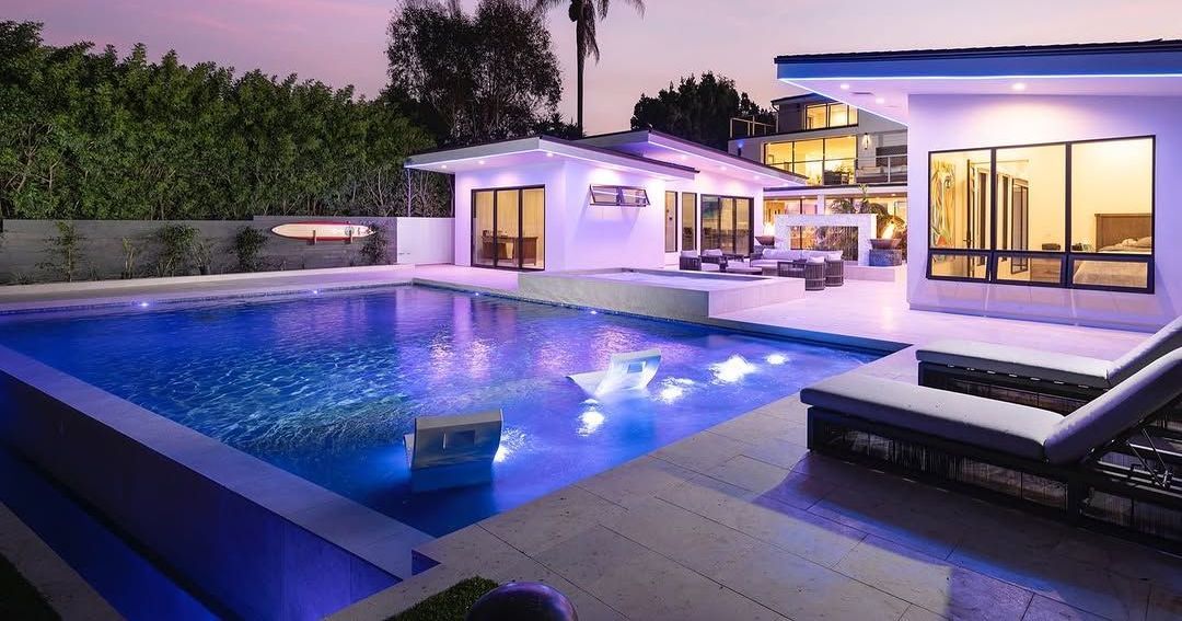 A large swimming pool is in the backyard of a house.