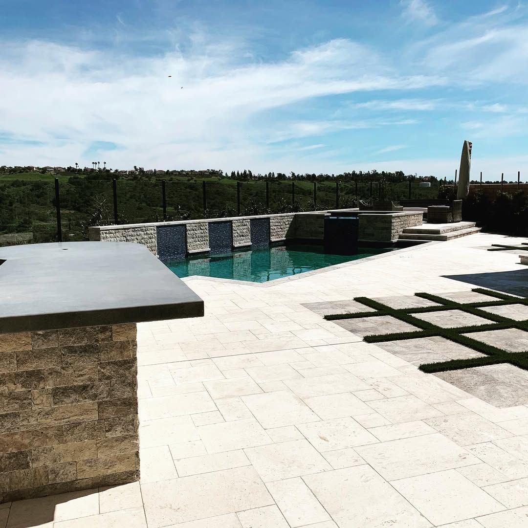 A large swimming pool is surrounded by a fence and a patio.