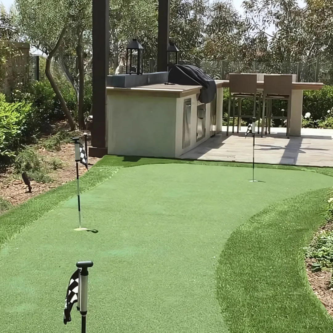 There is a putting green in the backyard with a patio in the background.