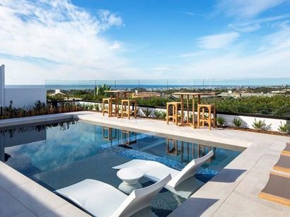 A large swimming pool with tables and chairs around it