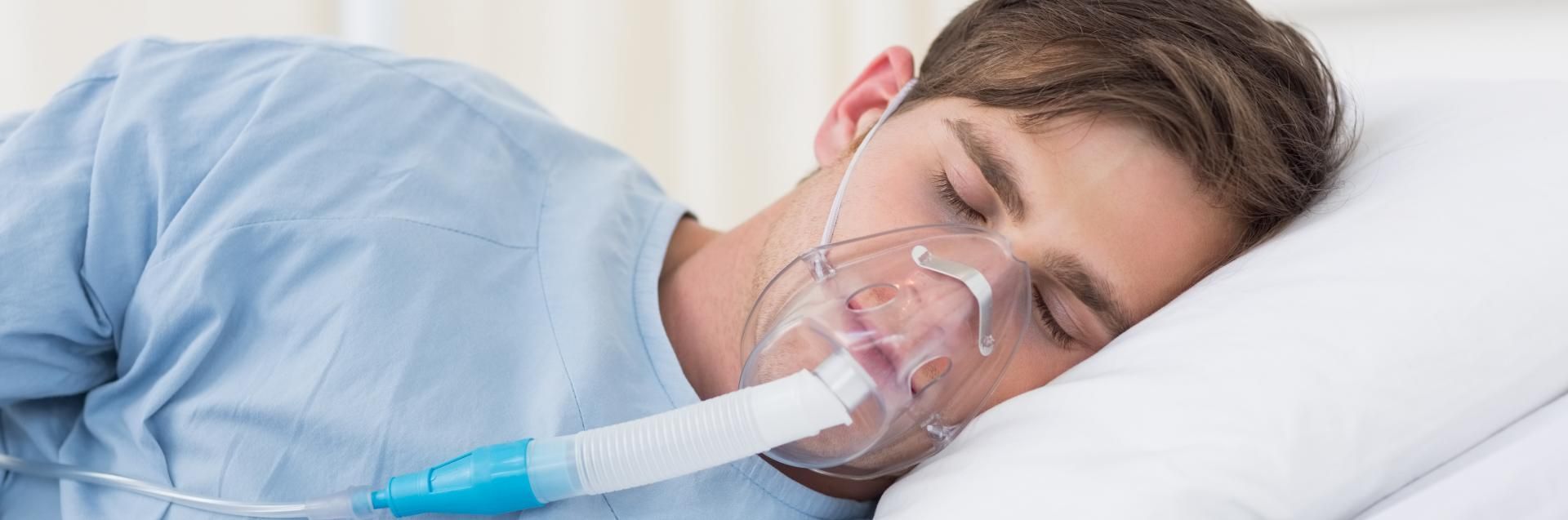 Person sleeping in bed with an oxygen mask and tube attached