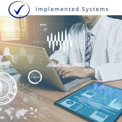 Office worker typing on laptop with digital interface graphics and “Implemented Systems” logo.