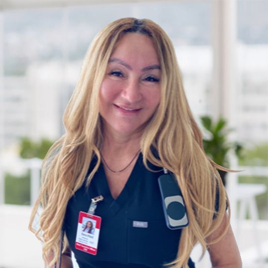 Blonde staff member in navy uniform with ID badge, smiling in a bright office setting