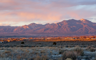 Sunlit mountains beyond a dry grassland under pink clouds at sunset