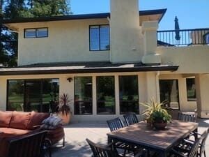 Backyard patio with outdoor seating, dining table, and a two-story modern house facade